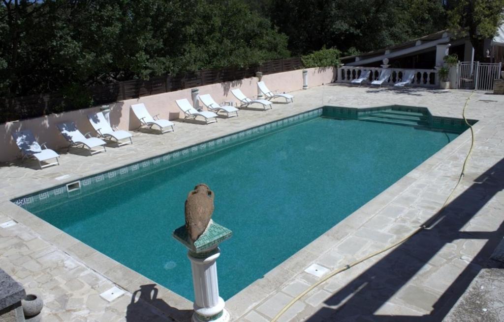 a swimming pool with chairs and a bird statue next to it at La Cadière in Lauris