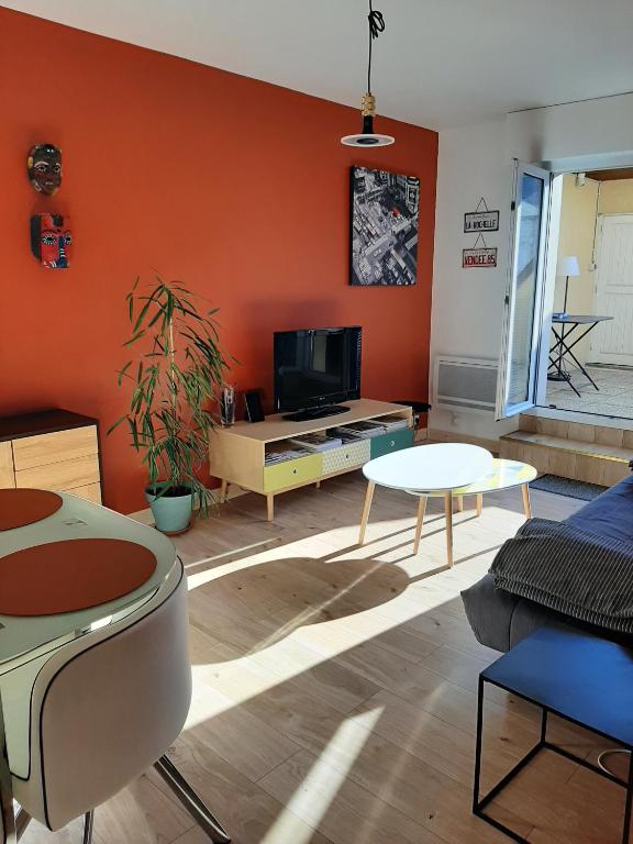 un salon avec un mur orange dans l'établissement CHARMANT APPARTEMENT CENTRE VILLE LE RONSARD, à Nogent-le-Rotrou