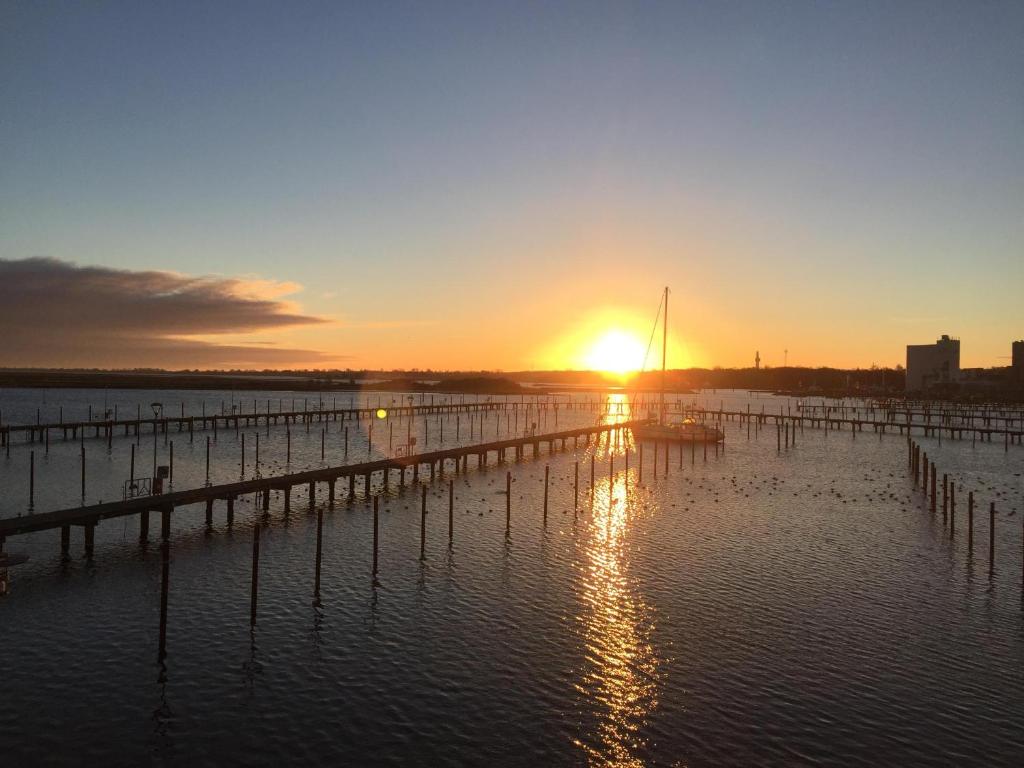 einen Sonnenuntergang über einem Dock mit einem Boot im Wasser in der Unterkunft Strandresort Heiligenhafen Strandresort 47 in Heiligenhafen