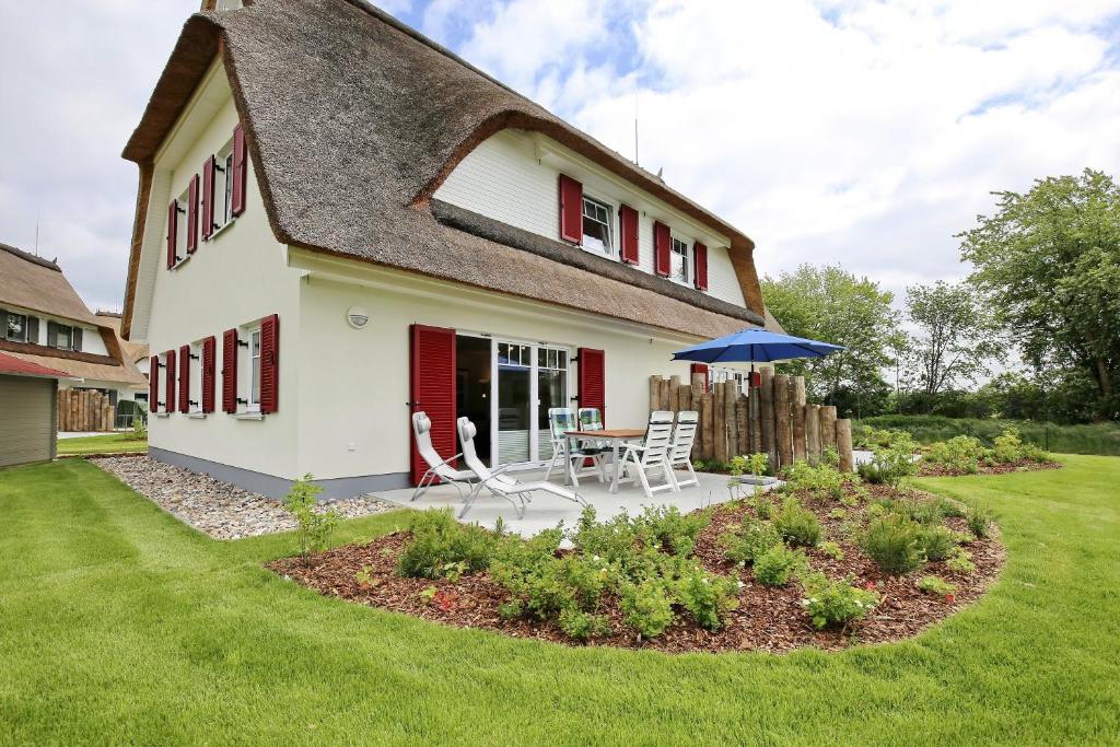 a white house with a table and chairs and an umbrella at Reethaus Sonnenschein in Boltenhagen