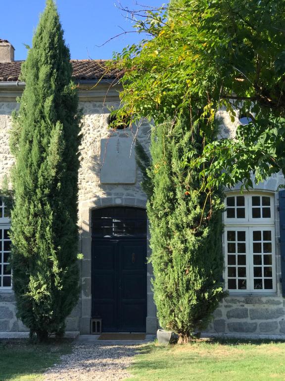 a house with a black door and two trees at Coeur de Calignac in Calignac