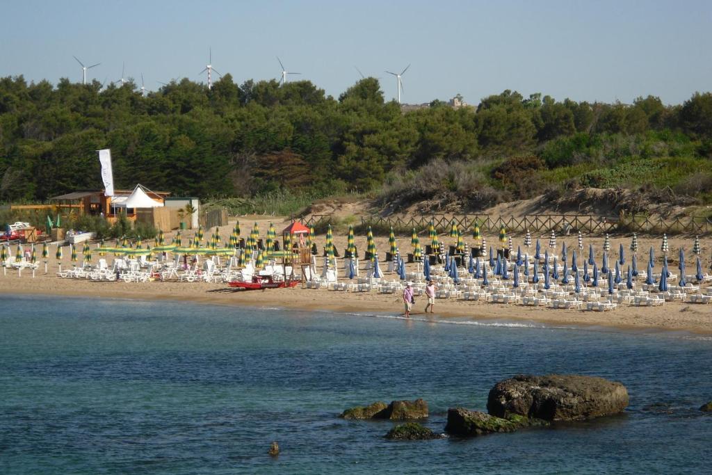 uma praia com cadeiras e guarda-sóis e um grupo de pessoas em RESIDENCE LA DARSENA em Isola di Capo Rizzuto