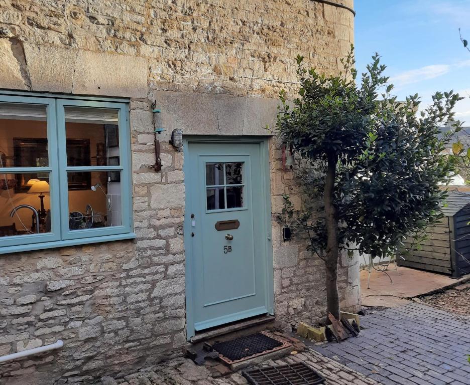 a house with a blue door and a tree at Market Place Cottage, Tetbury, Cotswolds Grade II Central location in Tetbury