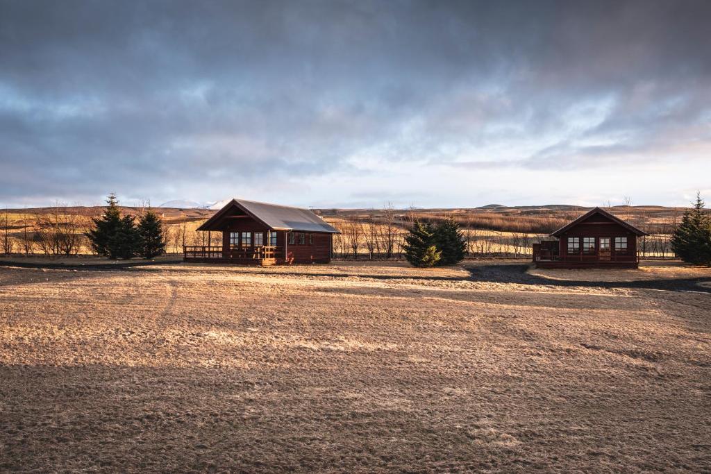 two buildings in a field next to a dirt road at Smáratún Cottages & Chalets in Hellisholar