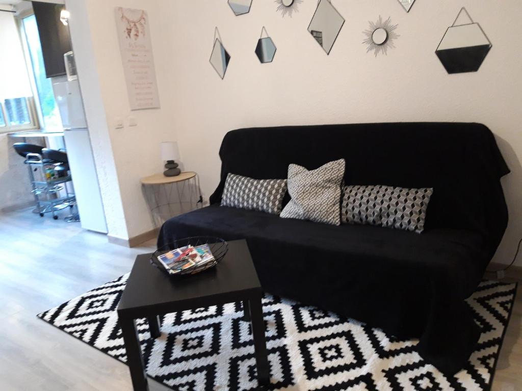 uma sala de estar com um sofá preto e uma mesa em Bandol Studio em Bandol