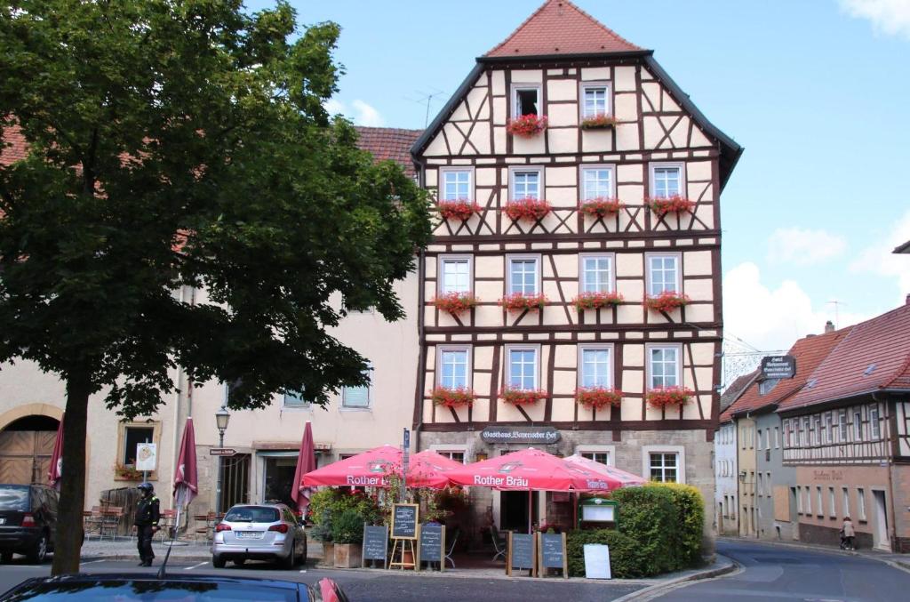 ein hohes Gebäude mit rosa Sonnenschirmen davor in der Unterkunft Hotel Bayerischer Hof in Münnerstadt