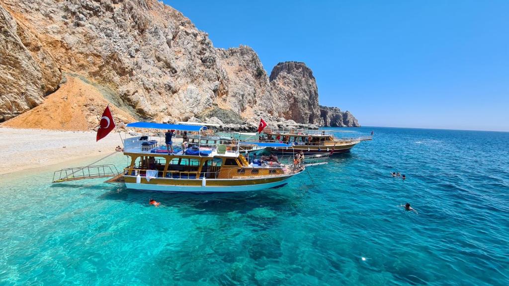 two boats in the water next to a beach at Papirus Hotel in Adrasan