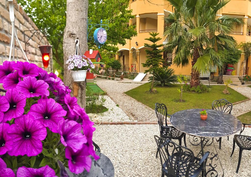 a garden with purple flowers and a table and chairs at Papirus Hotel in Adrasan