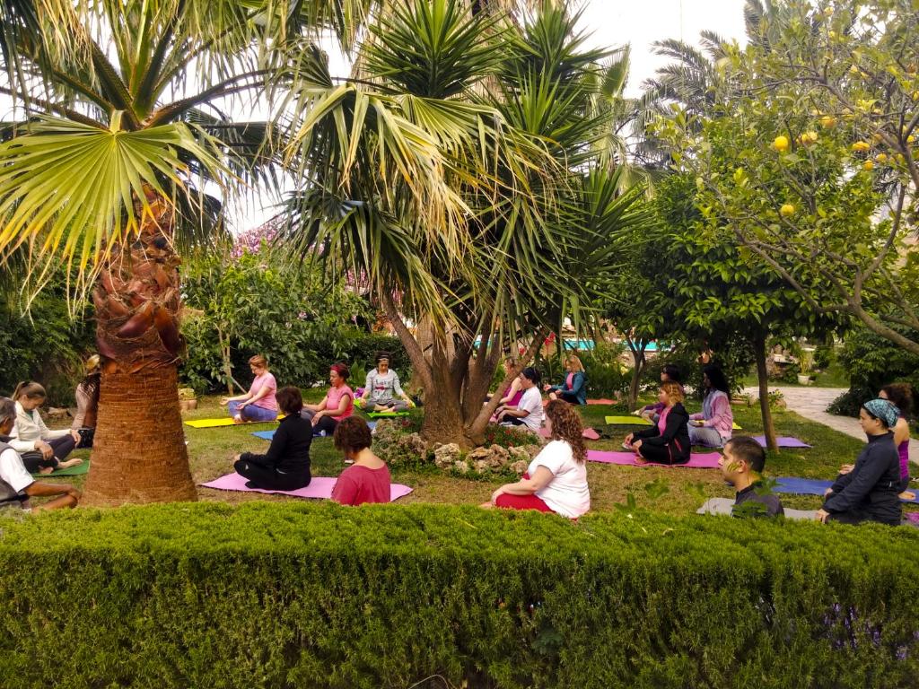 a group of people sitting in a park doing yoga at Papirus Hotel in Adrasan