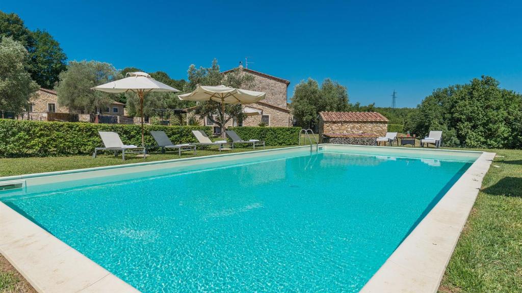 a swimming pool in a yard with chairs and umbrellas at FONTE CANNELLA 12&4, Emma Villas in Manciano