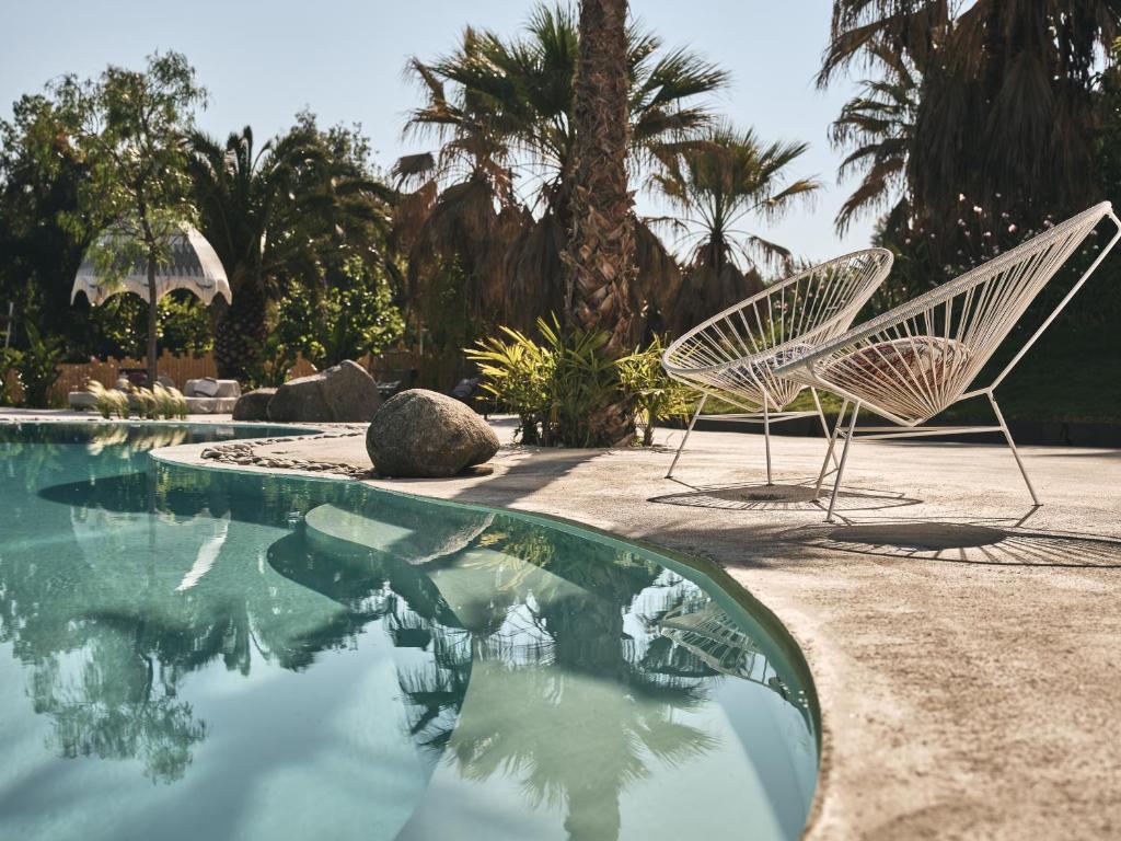 two white chairs sitting next to a swimming pool at Ekies All Senses Resort, a Member of Design Hotels in Vourvourou