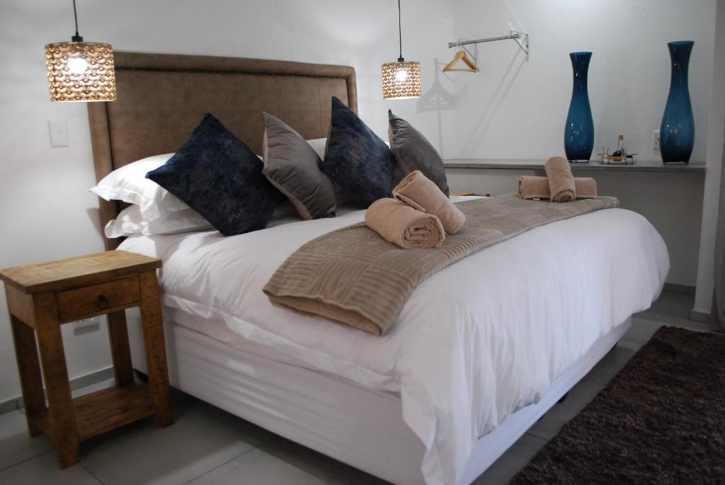 ein Schlafzimmer mit einem großen weißen Bett mit blauen Kissen in der Unterkunft Vaal De Vue Guesthouse in Christiana