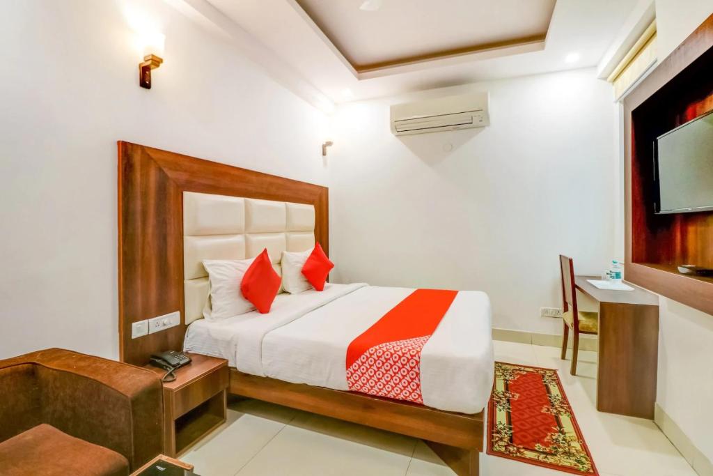 a bedroom with a bed with red pillows and a tv at Hotel Airport View in New Delhi