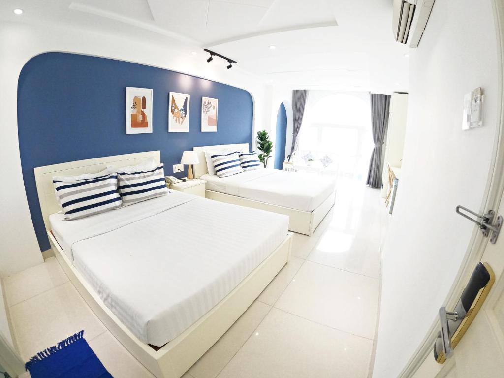 2 camas en una habitación blanca con paredes azules en Dinh Phat Hotel, en Ho Chi Minh