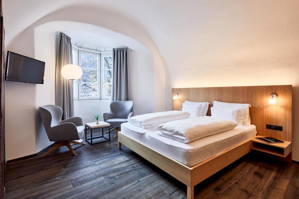 ein Hotelzimmer mit einem Bett und einem Stuhl in der Unterkunft Hotel Walther v.d. Vogelweide Superior in Klausen