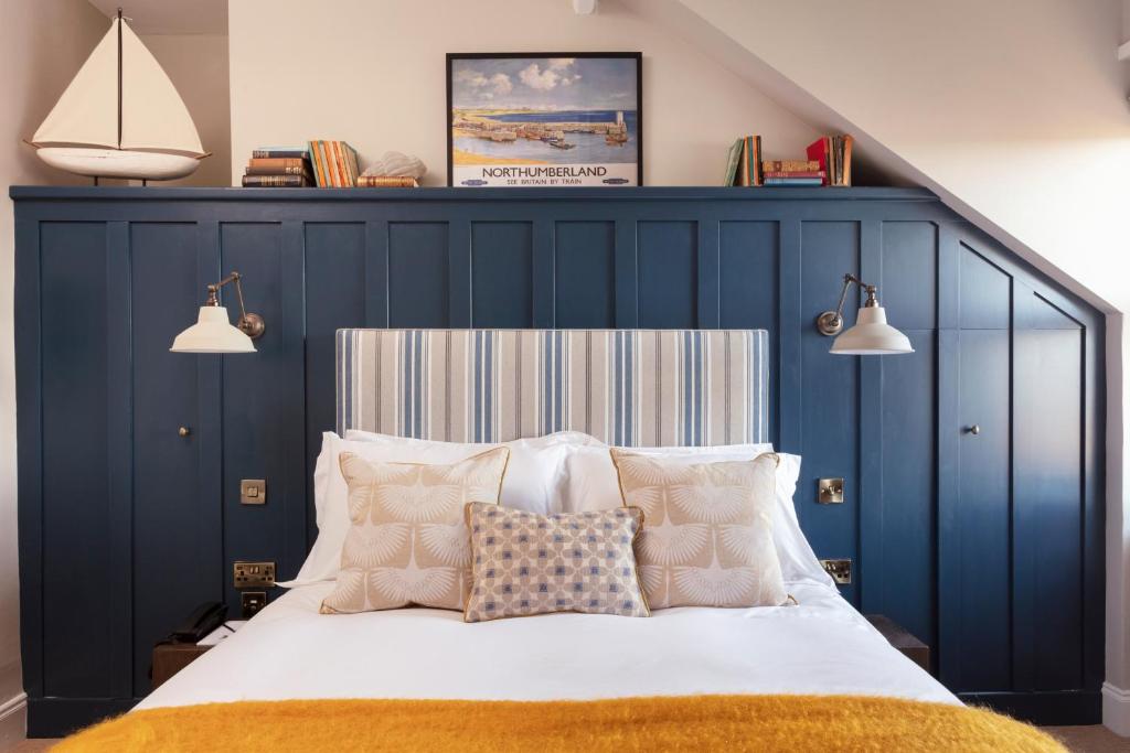 a bedroom with a large bed with a blue headboard at The Whittling House in Alnmouth