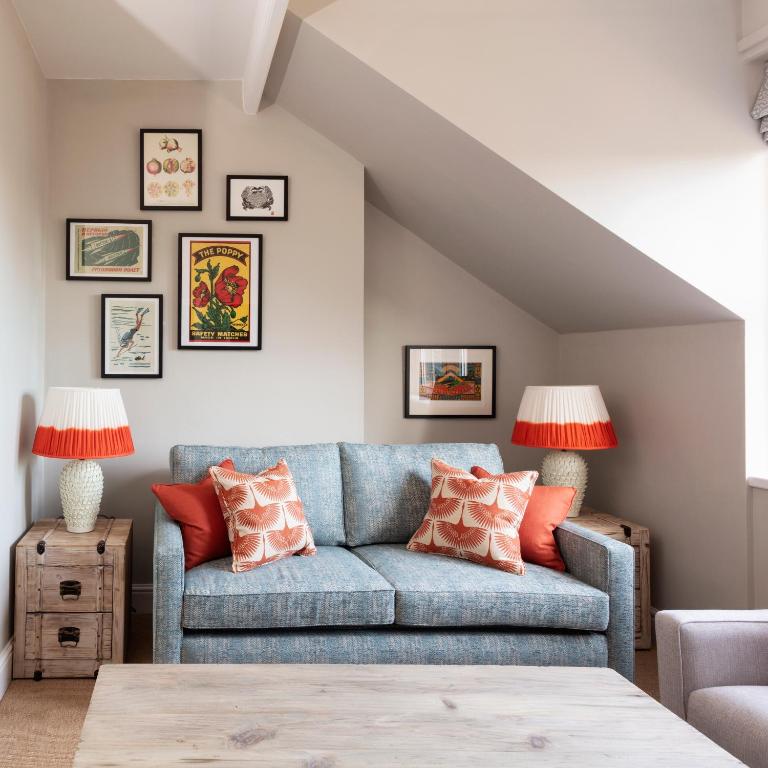 a living room with a blue couch with orange pillows at The Whittling House in Alnmouth
