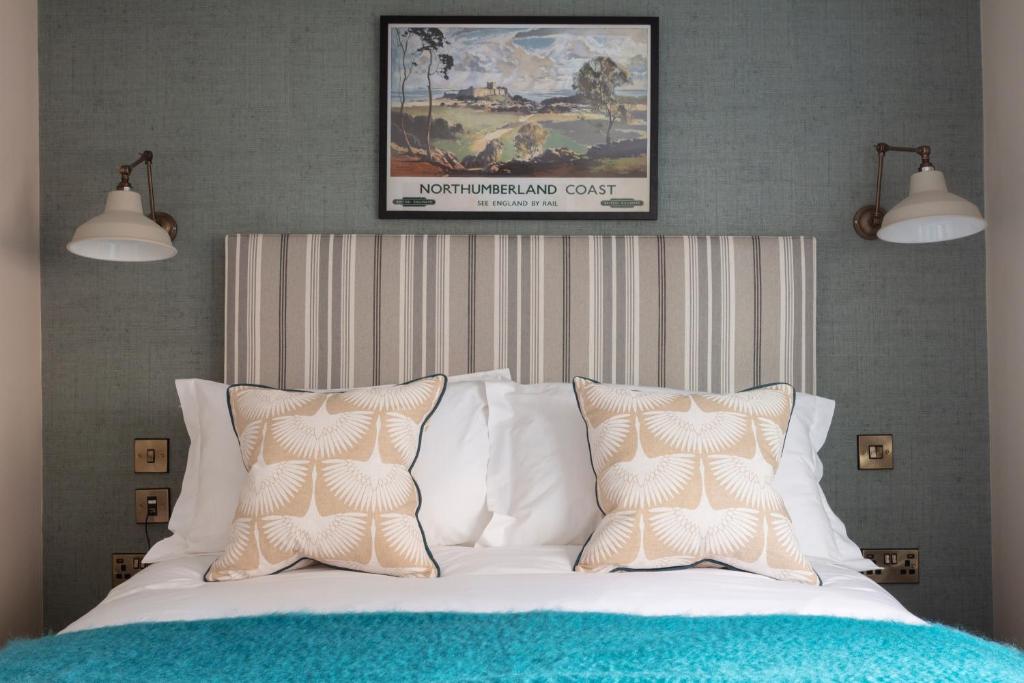 a bed with white sheets and pillows in a bedroom at The Whittling House in Alnmouth