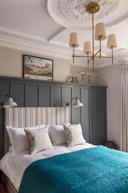 a bedroom with a large bed with a blue blanket at The Whittling House in Alnmouth