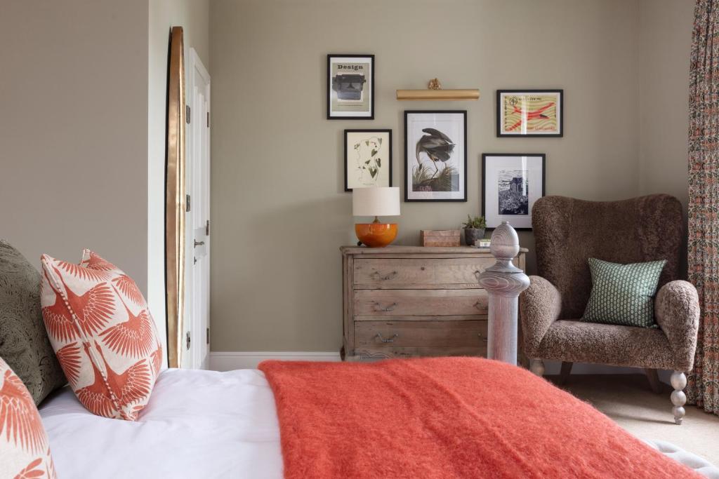 a bedroom with a bed with a dresser and a chair at The Whittling House in Alnmouth
