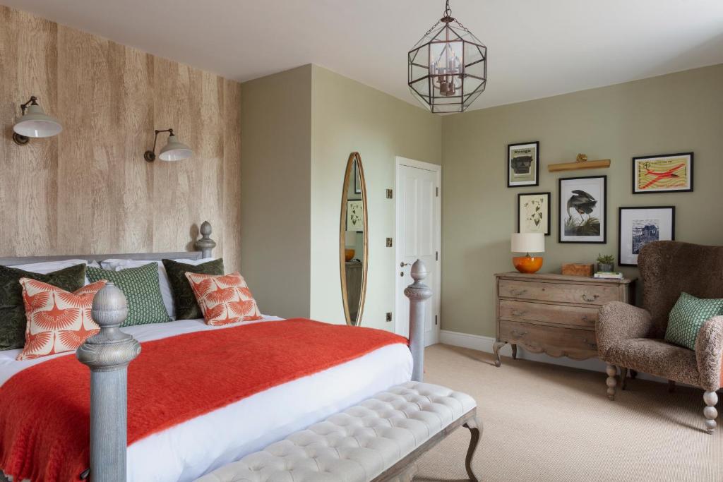 a bedroom with a bed and a chair and a mirror at The Whittling House in Alnmouth