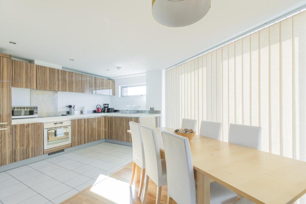 a kitchen with a wooden table and white chairs at Holborn City Living in London