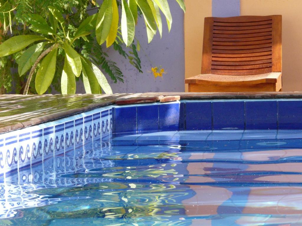 a swimming pool with blue tiles and a chair at Pousada O Refúgio in Jericoacoara