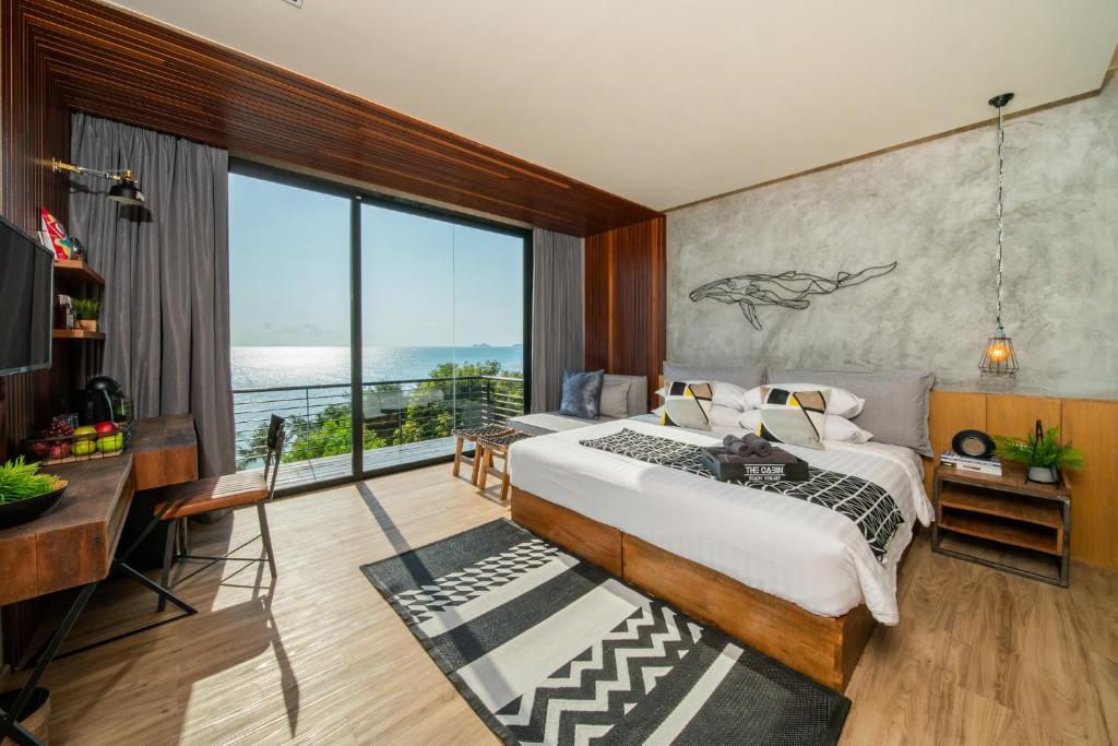 a bedroom with a bed and a large window at The Cabin Beach Resort in Haad Rin