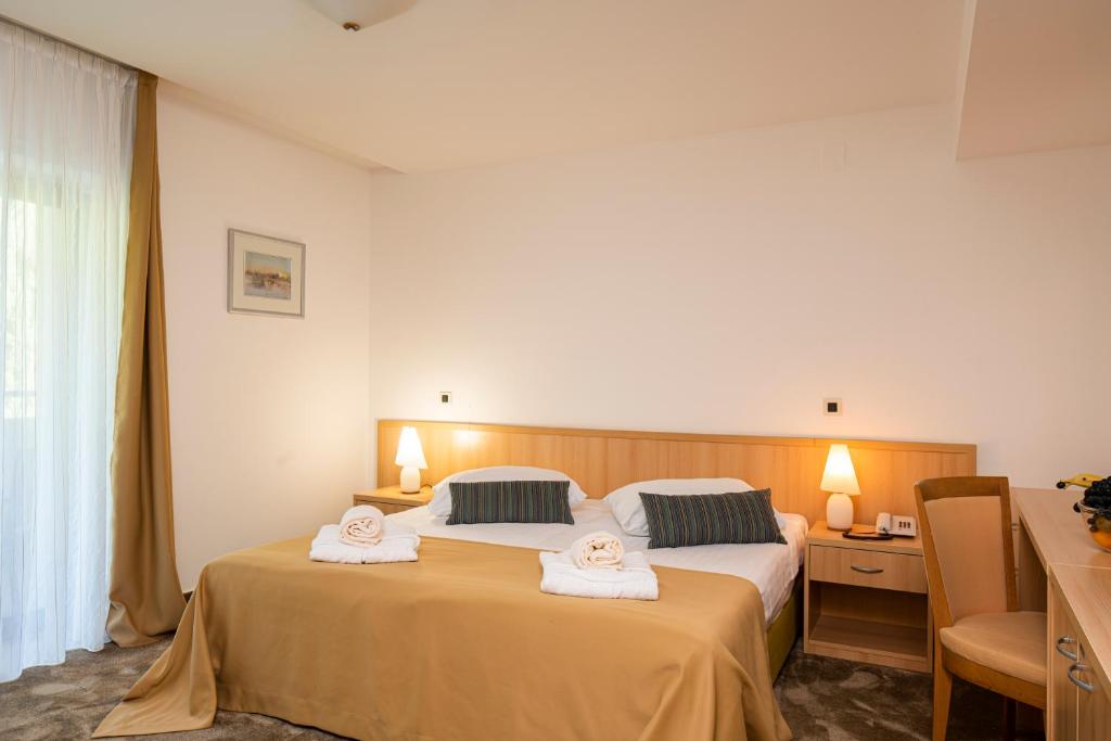 a hotel room with two beds with towels on them at Hotel Flores in Poreč