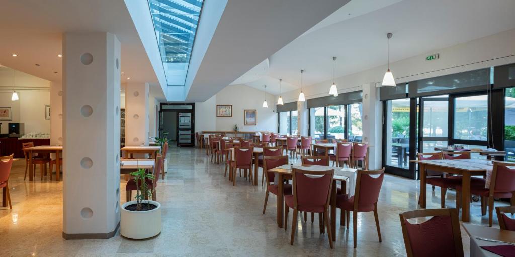 a dining room with tables and chairs and windows at Hotel Flores in Poreč