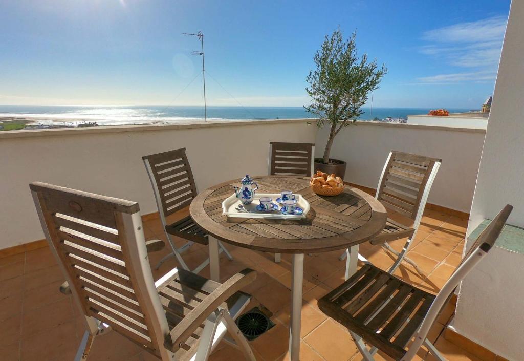 einen Tisch und Stühle mit Meerblick in der Unterkunft Terraza Trafalgar Apartamento tipo penthouse con enorme terraza y vistas al mar in Conil de la Frontera