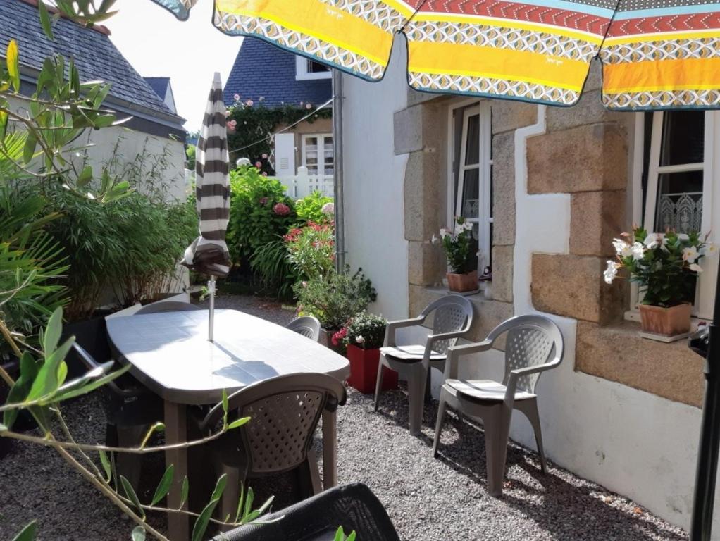 un patio con tavoli, sedie e ombrellone di Maison typique de pêcheur, rénovée avec wifi à PERROS-GUIREC - Réf 867 a Perros-Guirec