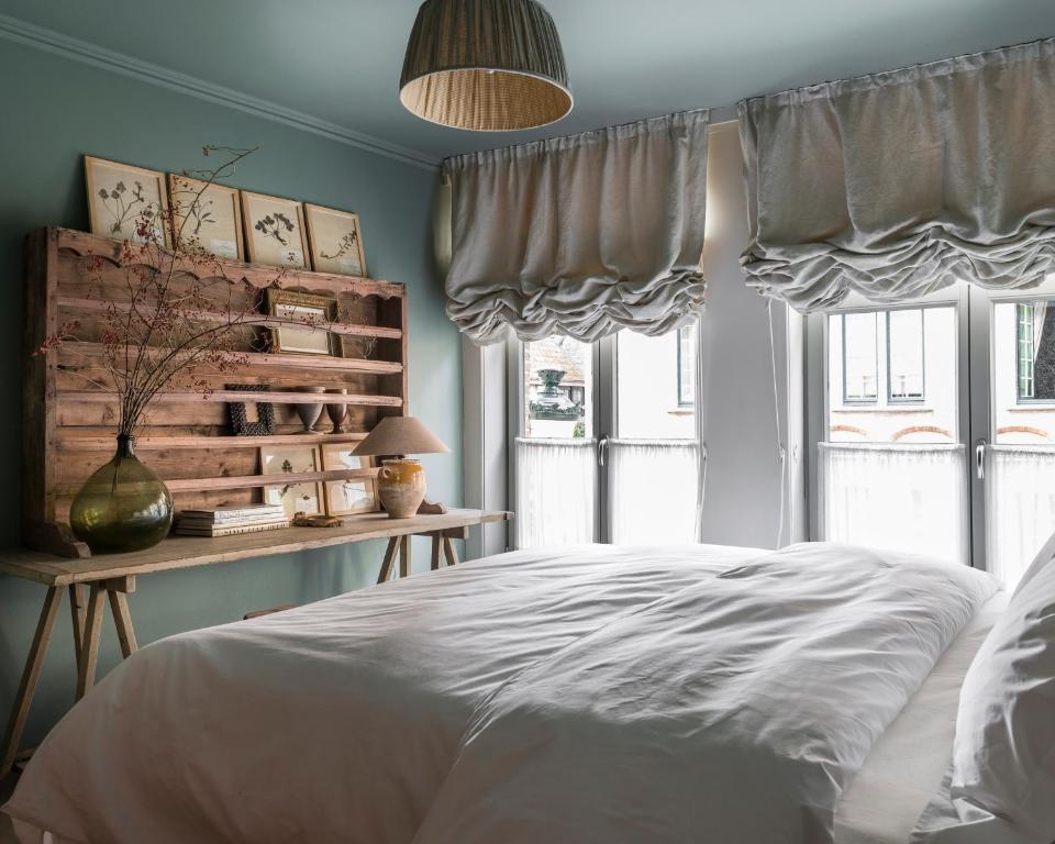 a bedroom with a bed and a table with windows at Guesthouse Dijver - Serene Escape in the Heart of Historic Bruges in Bruges