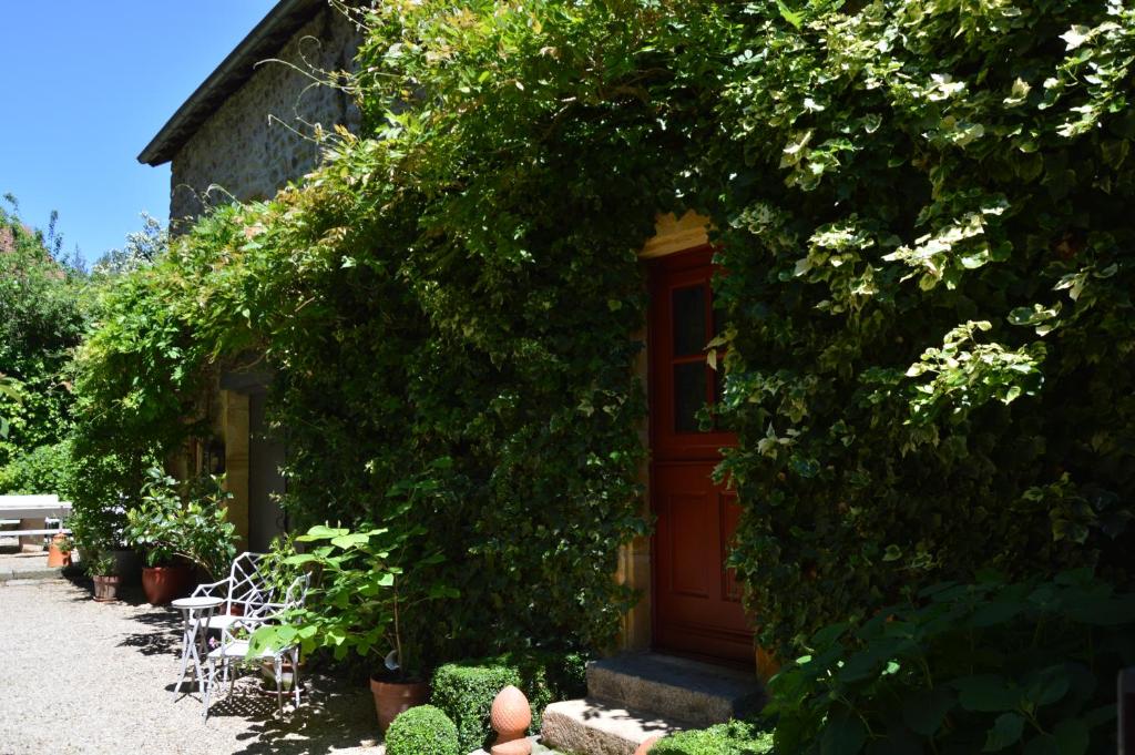 un bâtiment avec une porte rouge recouverte de lierre dans l'établissement Maison d'hôtes - Les Tillets, à Bois-Sainte-Marie