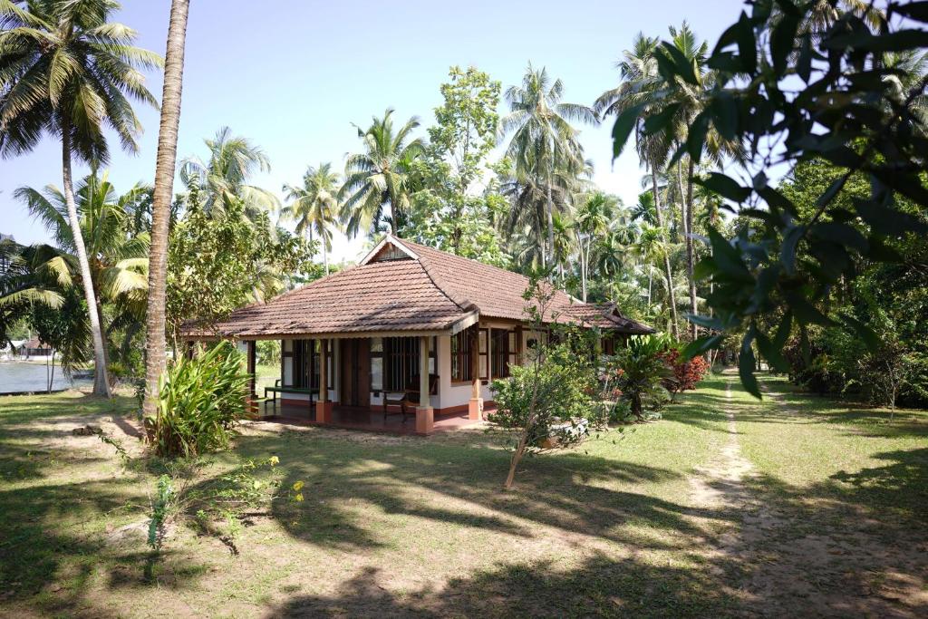 a house in the middle of a yard with palm trees at Gramam Homestay, Cochin in Cochin