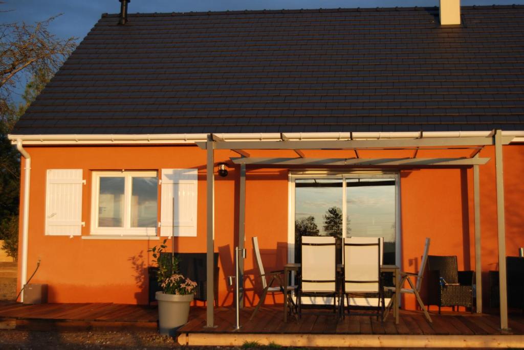 une maison orange avec des chaises et une table sur une terrasse dans l'établissement Gite Labradors De Bailly - Giverny, à Saint-Pierre-la-Garenne