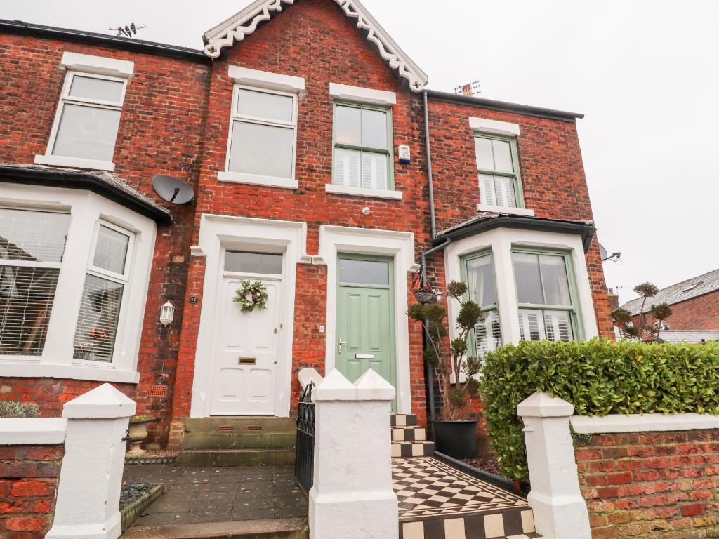 a red brick house with a green door at Westwood House in Lytham St Annes