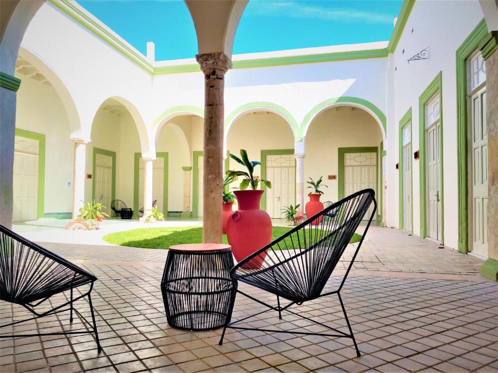 2 sillas en un patio con un jarrón en Hotel Boutique La Casona by Kavia en Mérida