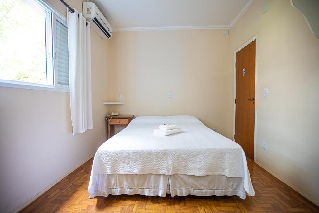 a white bedroom with a bed and a window at Casarão Hotel in Brotas