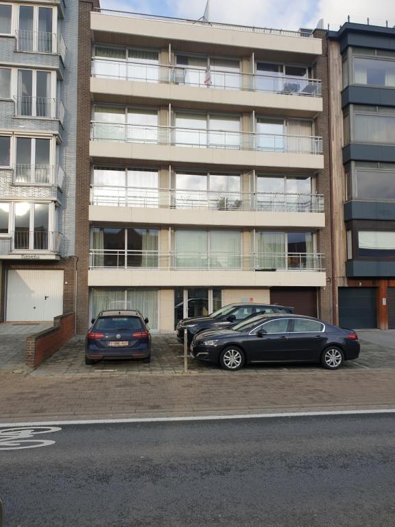 twee auto's geparkeerd op een parkeerplaats voor een gebouw bij Appartement, residentie Syci in Koksijde