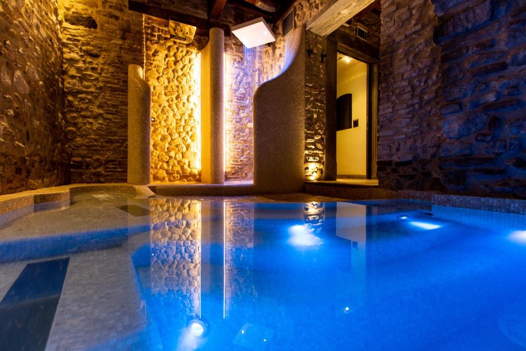 a swimming pool in a building with a stone wall at Oste del Castello Wellness & Bike Hotel in Verucchio