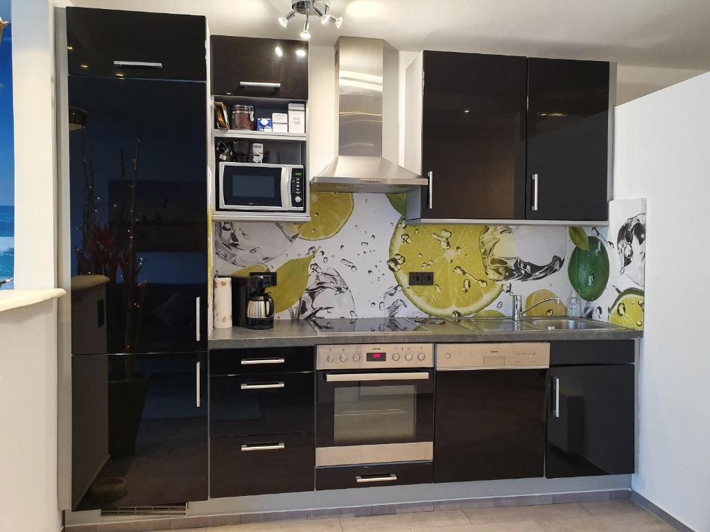 uma cozinha com armários pretos e electrodomésticos de aço inoxidável em Vier Jahreszeiten Haus 1 Whg 20 em Grossenbrode