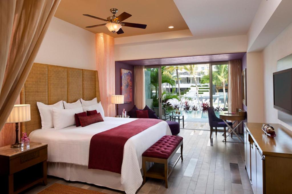 a hotel room with a large bed and a television at Secrets Vallarta Bay Resort & SPA - Adults Only in Puerto Vallarta