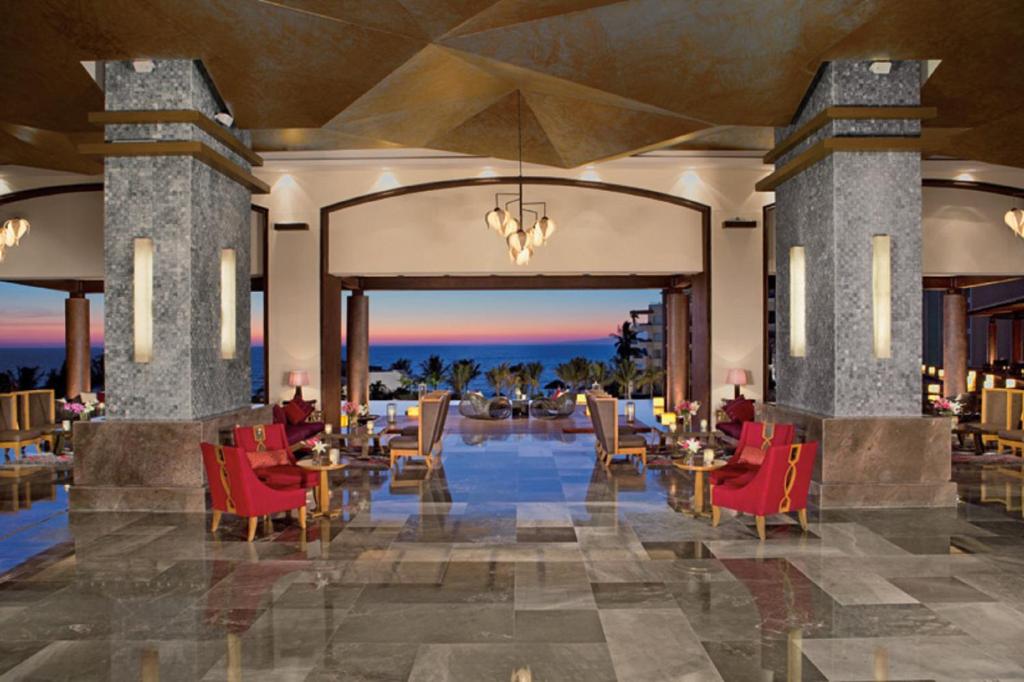 a lobby of a resort with red chairs and tables at Secrets Vallarta Bay Resort & SPA - Adults Only in Puerto Vallarta