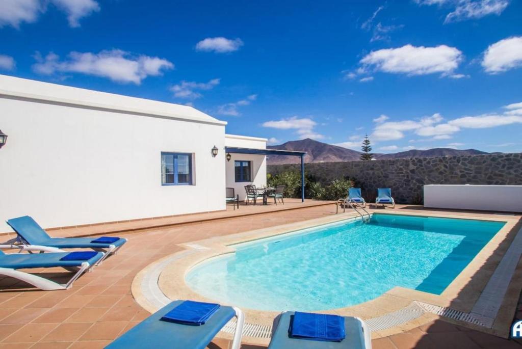 een zwembad met stoelen en een huis bij Villa Tamia & Atlántico Marina Rubicón in Playa Blanca