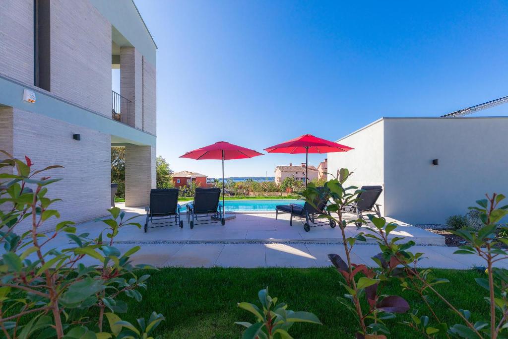 a patio with chairs and umbrellas next to a pool at Villen Matija & Mima in Fažana