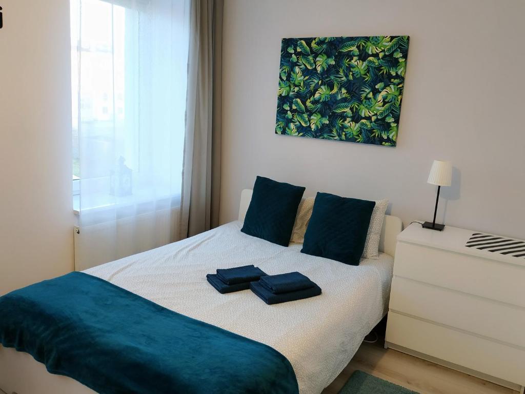 a bedroom with a bed with blue pillows on it at theApartments Manufaktura in Łódź