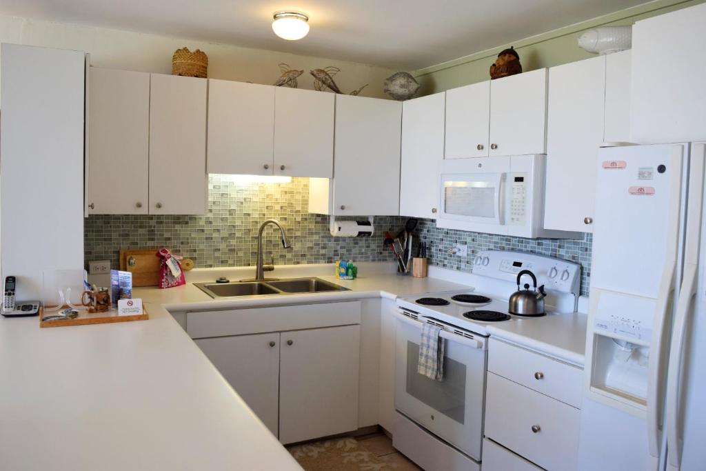 a white kitchen with white cabinets and a sink at Hale Kai O'Kihei 109 in Kihei