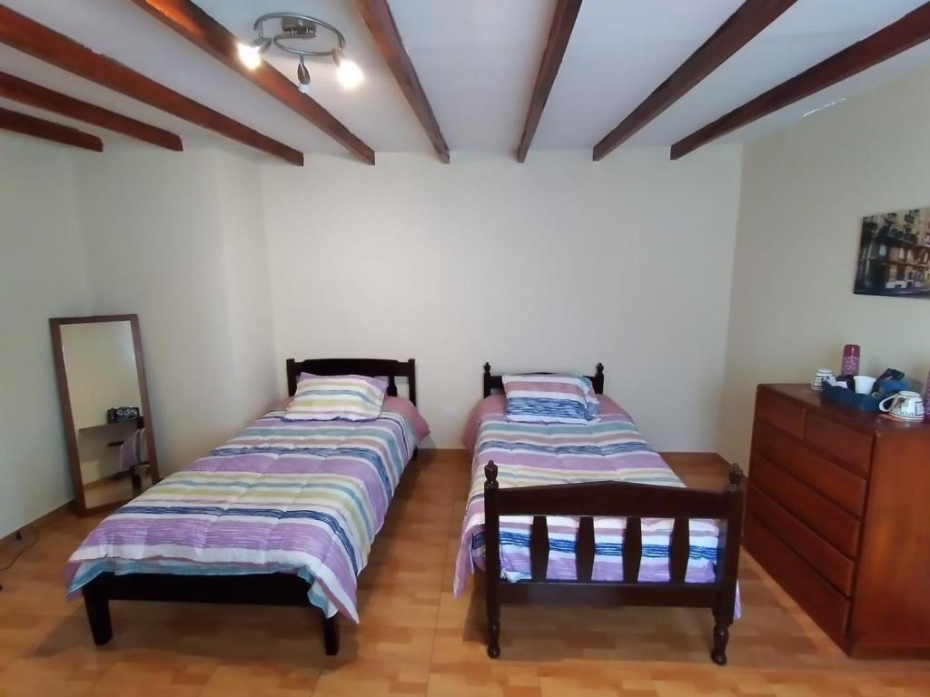two twin beds in a room with a dresser at ENHEBRA HOUSE in Lima