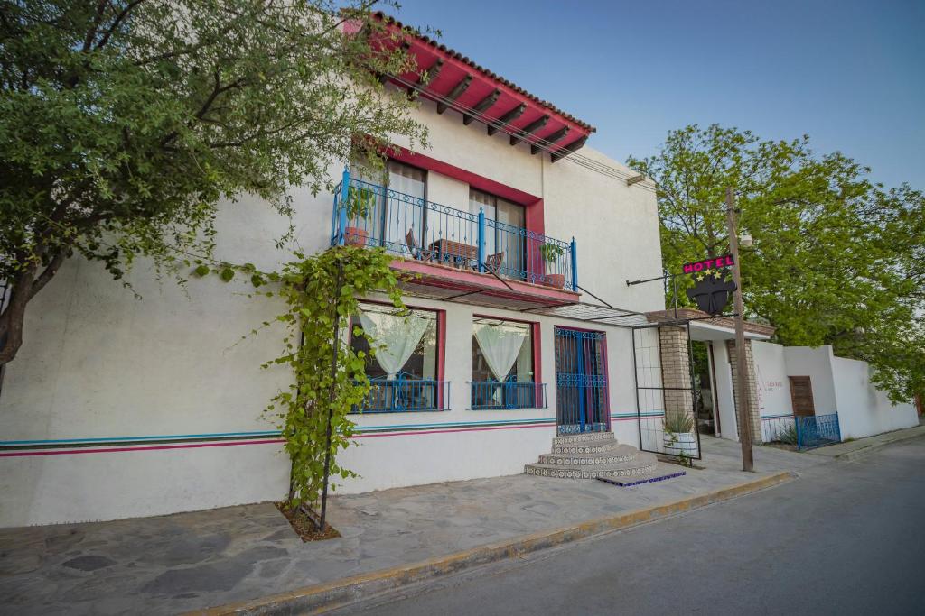 a white building with red and blue windows on a street at Casa Maru Hotel in Parras de la Fuente